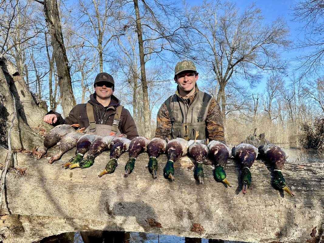 Two young hunters smile with their haul of dead waterfowl. 